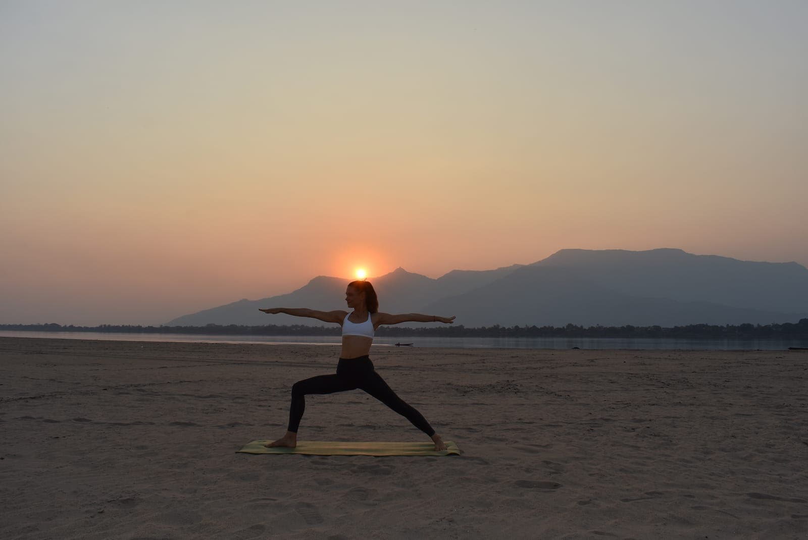Warrior II with arms wide at sunset on the beach